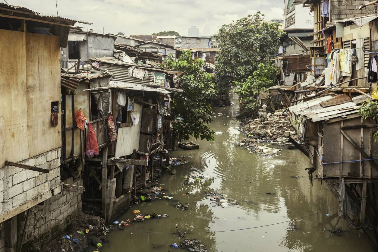 Hütten in einem Slum-Gebiet mit verschmutztem Kanal
